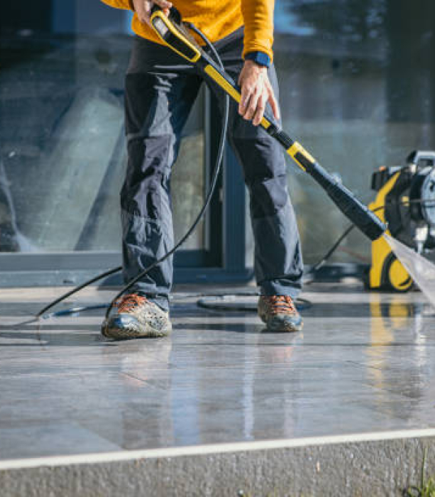 Man cleaning the terrace with high pressure cleaner on beautiful sunny day.